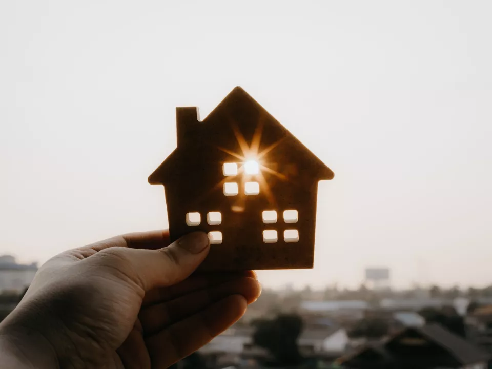 a small image of a hand holding a cardboard house